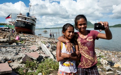 Mary Ann, 10, and Mary Grace, 14, take a selfie front of Anibong Bay in Tacloban, Philippines. Photo: Eleanor Farmer/Oxfam