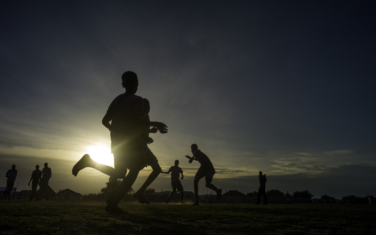 Children play soccer as the sun sets over a camp for displaced people in Mingkaman, South Sudan. Oxfam is working in the camp to provide clean water and sanitation. Photo: Kieran Doherty/Oxfam
