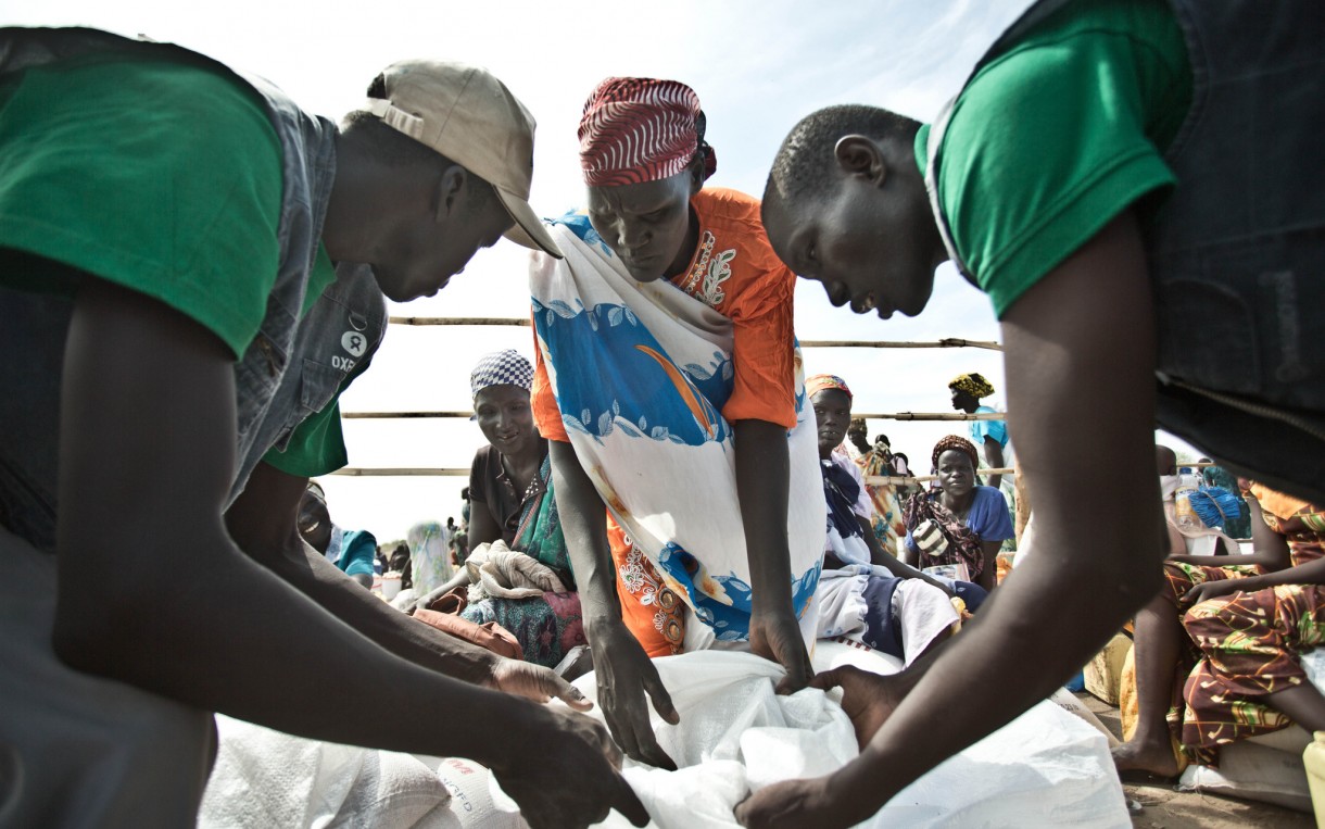 Oxfam aid workers in Mingkaman, South Sudan, oversee the distribution of food to displaced people like Martha Nyandit, pictured, a mother of six. Photo: Pablo Tosco/Oxfam