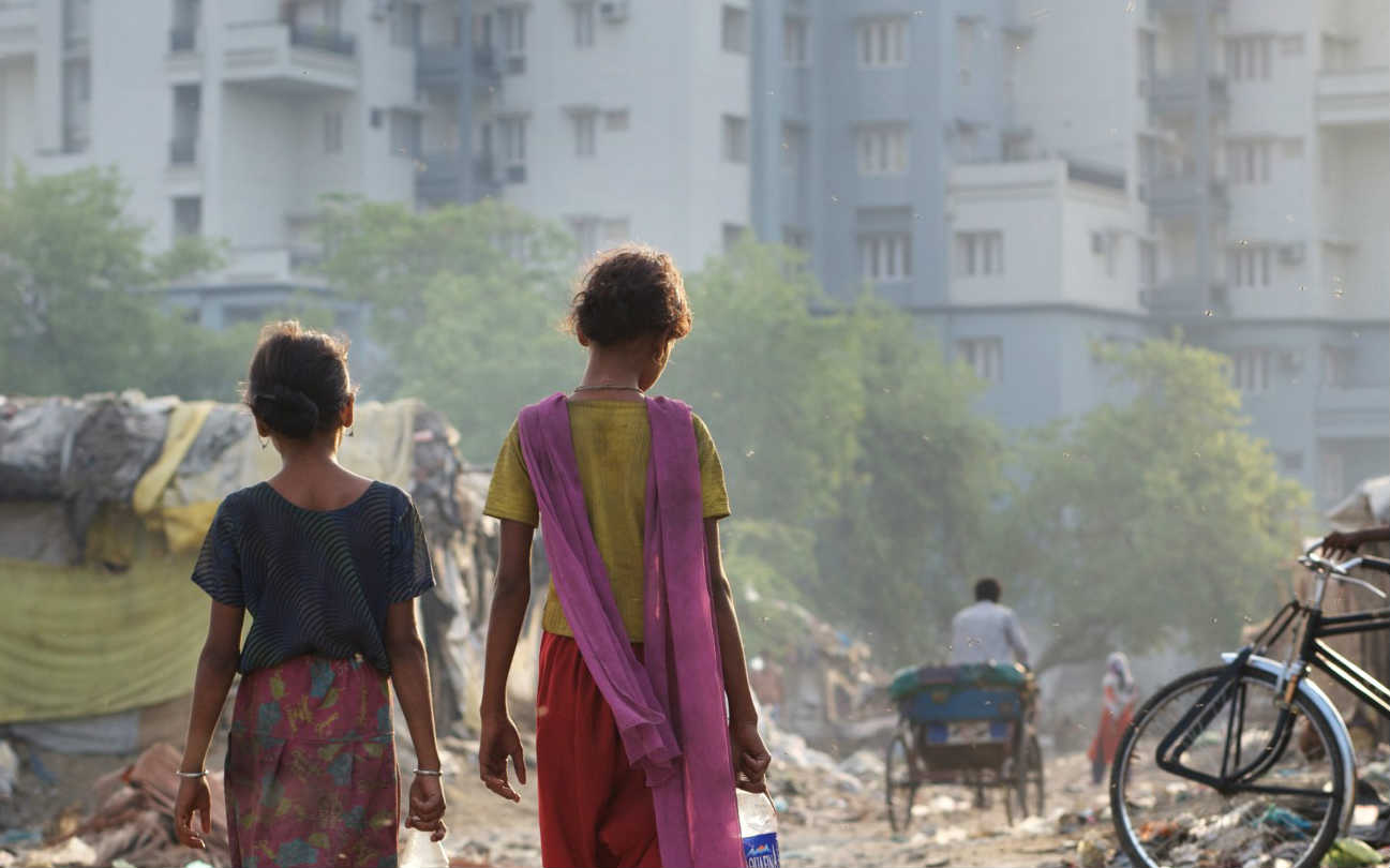 Housing for the wealthier middle classes rises above the insecure housing of a slum community in Lucknow, India. Photo: Tom Pietrasik / Oxfam