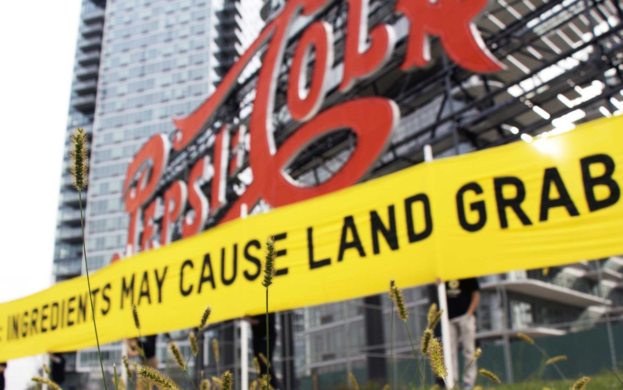 Oxfam volunteers hold a banner reading "Caution: Ingredients may cause land grabs" outside of PepsiCo headquarters in New York City in October 2013. Photo: Vasia Markides/Oxfam America