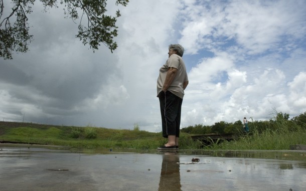 "Miss Betty" of Chauvin, Louisiana stands on the foundation of her former home, which was ruined by a hurricane in 2007. Coastal restoration programs can improve resiliency of areas to withstand storms, strengthen communities and the economy, and restore degraded ecosystems. Photo: Valerie Downes / Oxfam America