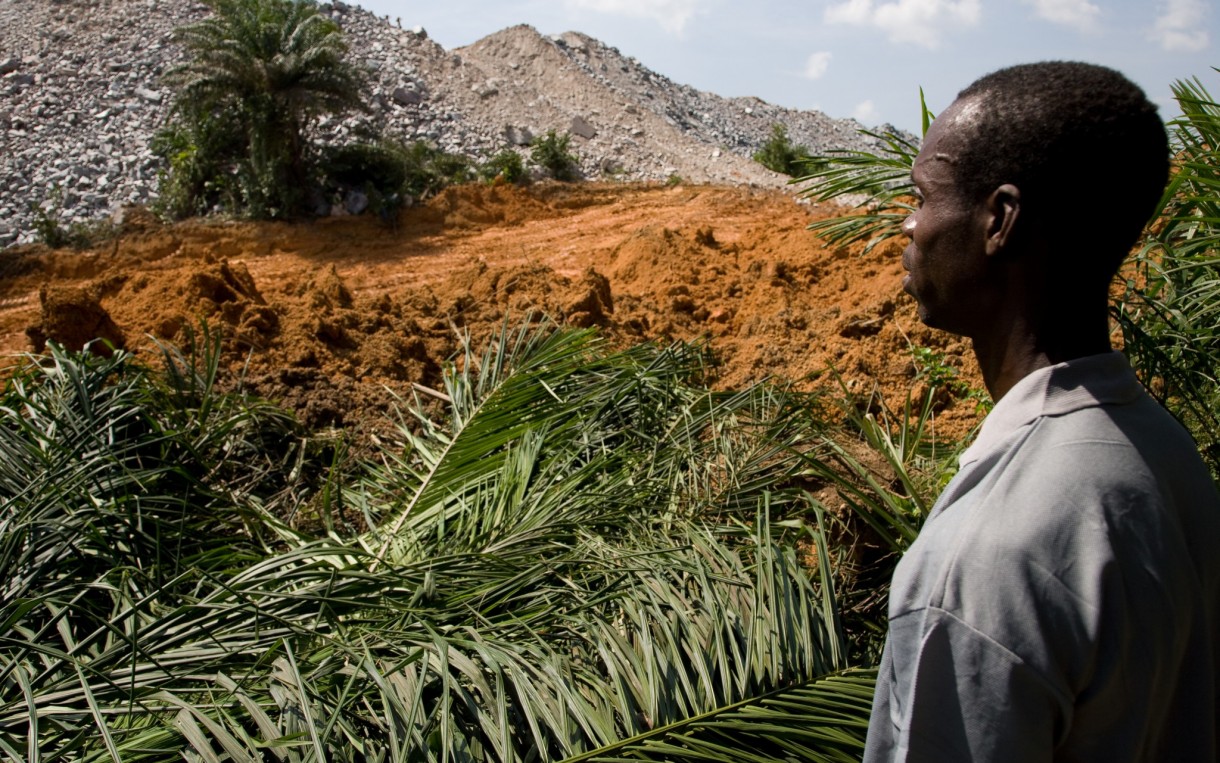 Waste rock from a nearby mine is encroaching on the relocated village of Teberebie, Ghana. Communities relocated to make way for gold mines in Ghana struggle with loss of agricultural land, unemployment, and environmental damage. Photo: Neil Brander/Oxfam America